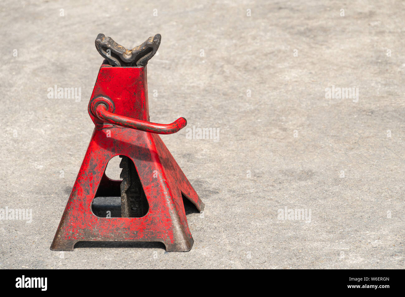 Used red high lift jack stand on the floor. Stock Photo