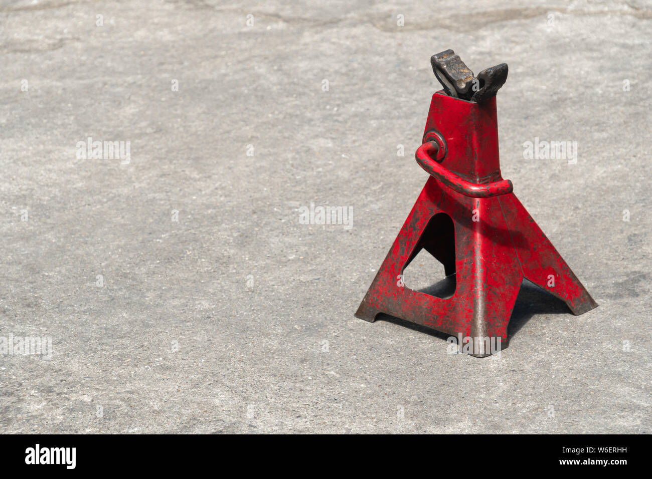 Used red high lift jack stand on the floor. Stock Photo