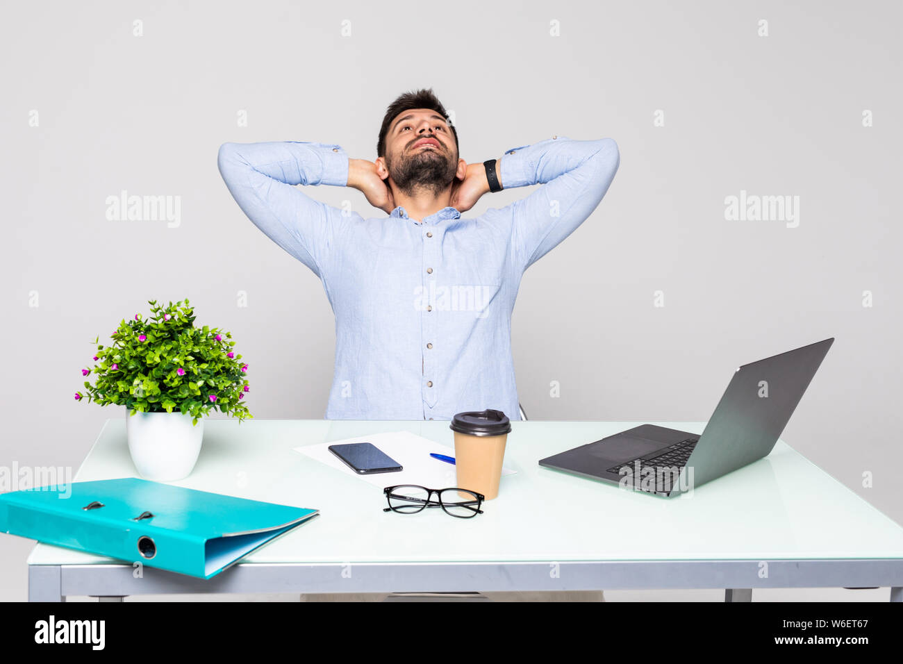 Happy man sitting at table in office and stretching himself Stock Photo ...