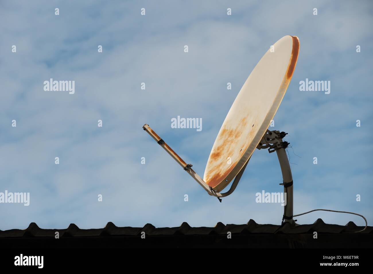 broken and old satellite dish on the roof and blue sky background Stock