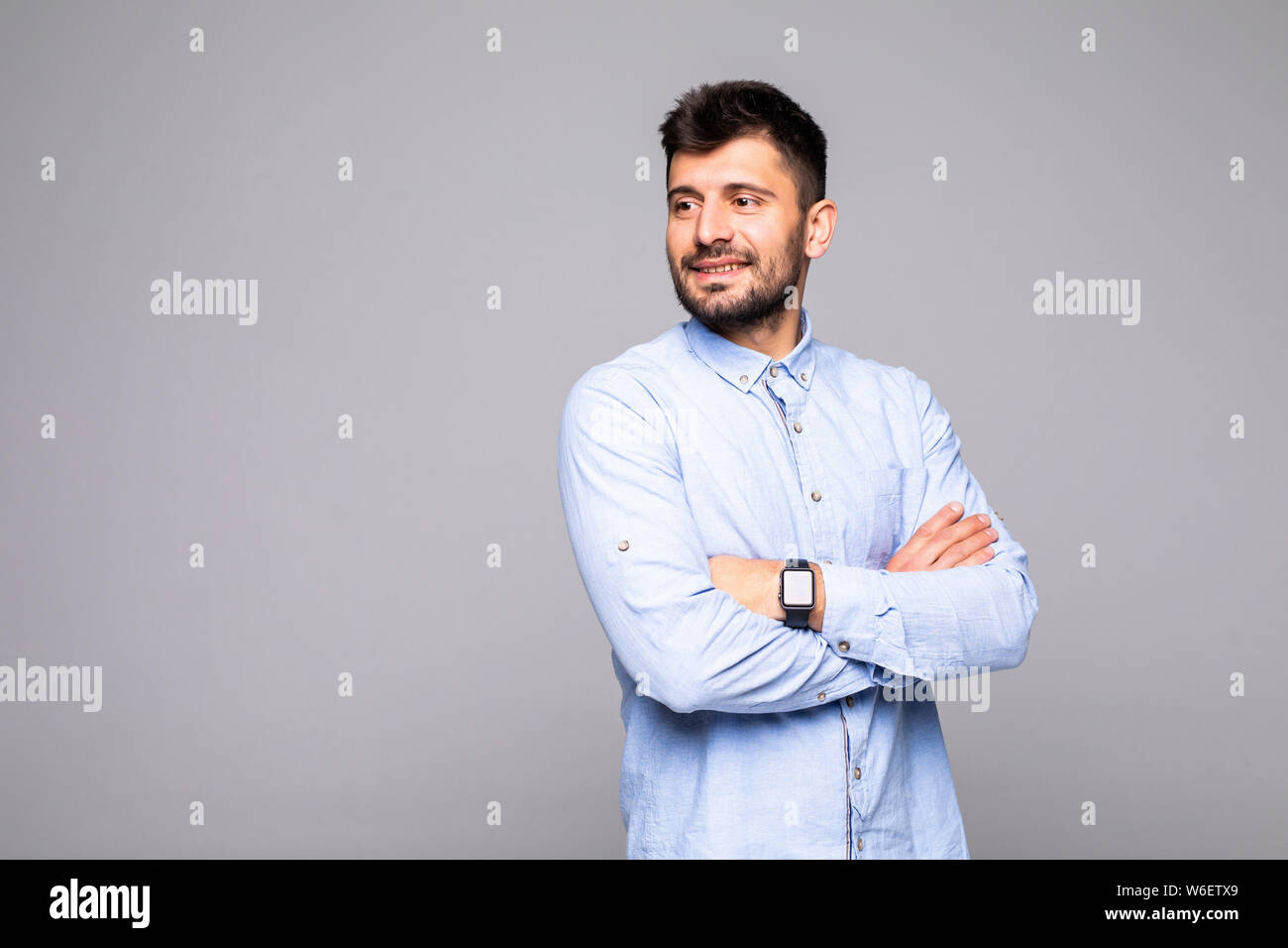 Portrait cool man having his arms crossed, looking at camera, isolated on grey background Stock Photo