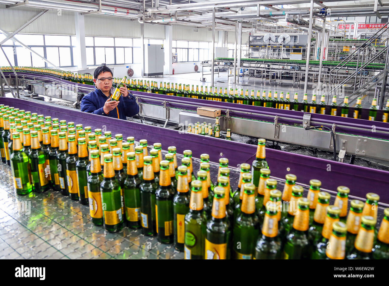 --FILE--A Chinese worker checks bottles of beer on the assembly line at ...