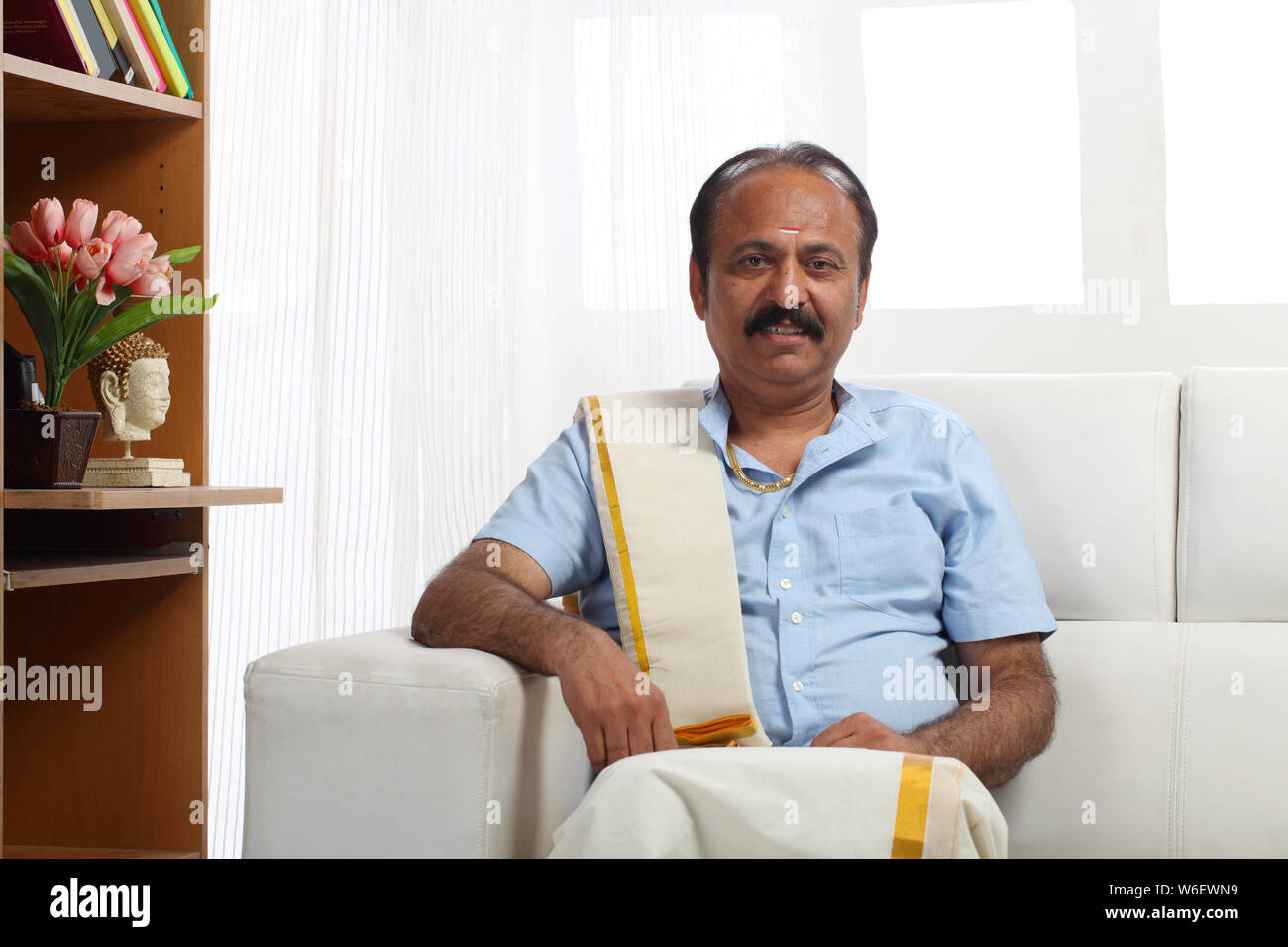 South indian man sitting on couch at home Stock Photo - Alamy