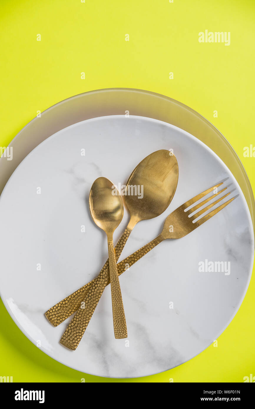 Top view of place setting with plate, knife and fork isolated on yellow