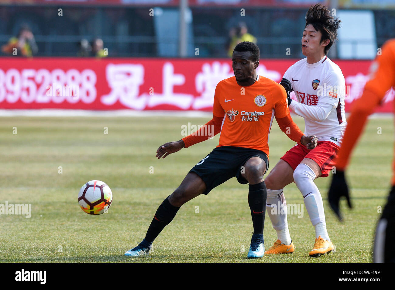 Cameroonian football player Benjamin Moukandjo, left, of Beijing Renhe kicks the ball to make a pass against a player of Tianjin Quanjian in their sec Stock Photo