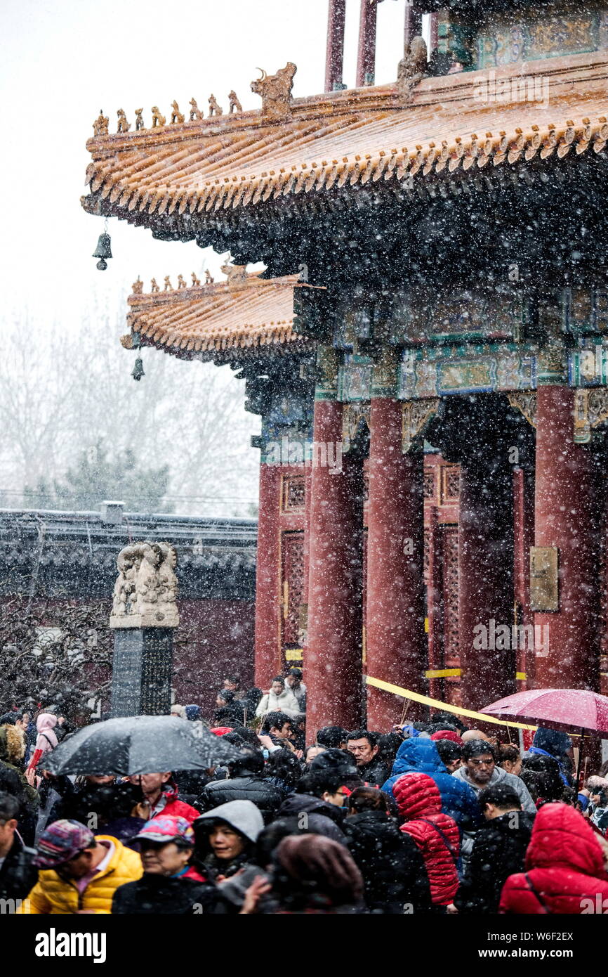 Tourists visit the Yonghe Temple, also known as the Yonghe Lamasery or Lama Temple, during a snowfall in Beijing, China, 17 March 2018. Stock Photo