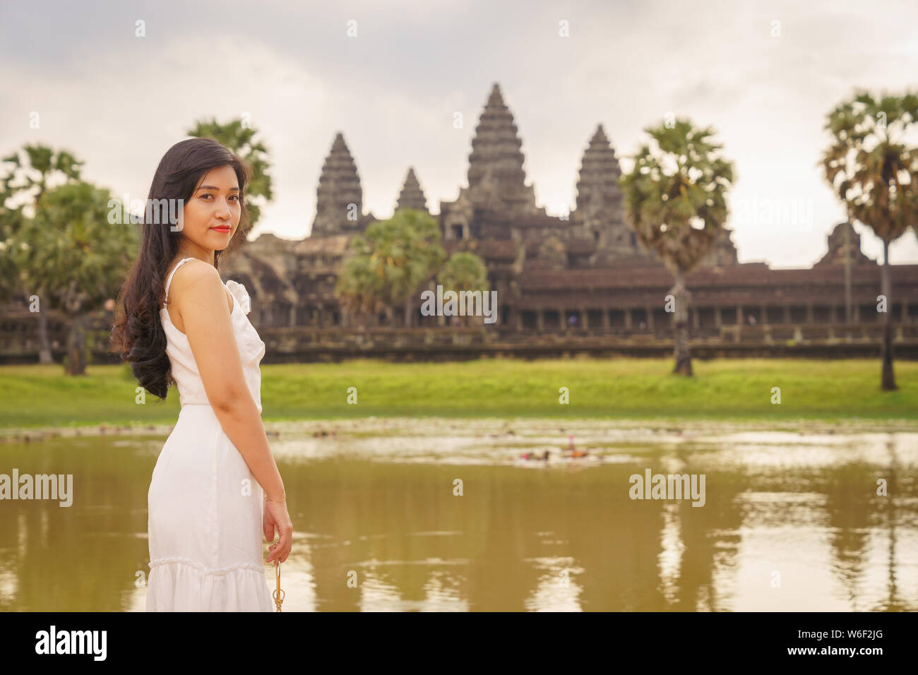 Emancipated Asian solo woman traveler exploring the temple of Angkor Wat, Siem Reap, Cambodia in white dress Stock Photo