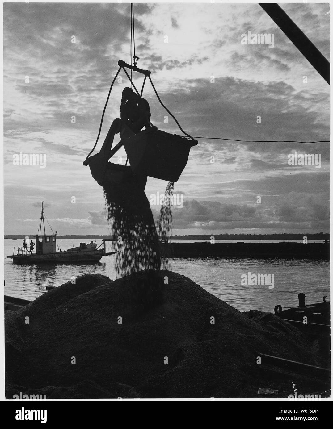 Africa. Cameroons. While the old port facilities are in constant use, work on expansion continues as long as there is light. The crane is unloading crushed rock to be used in construction of new wharves Stock Photo