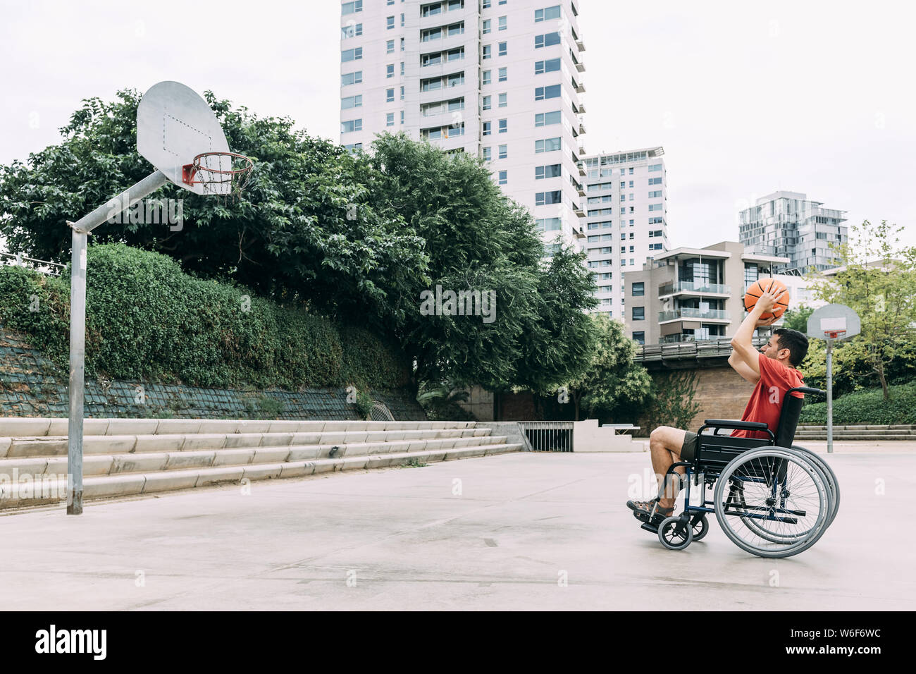 handicapped man in wheelchair throwing ball to basket alone, concept of