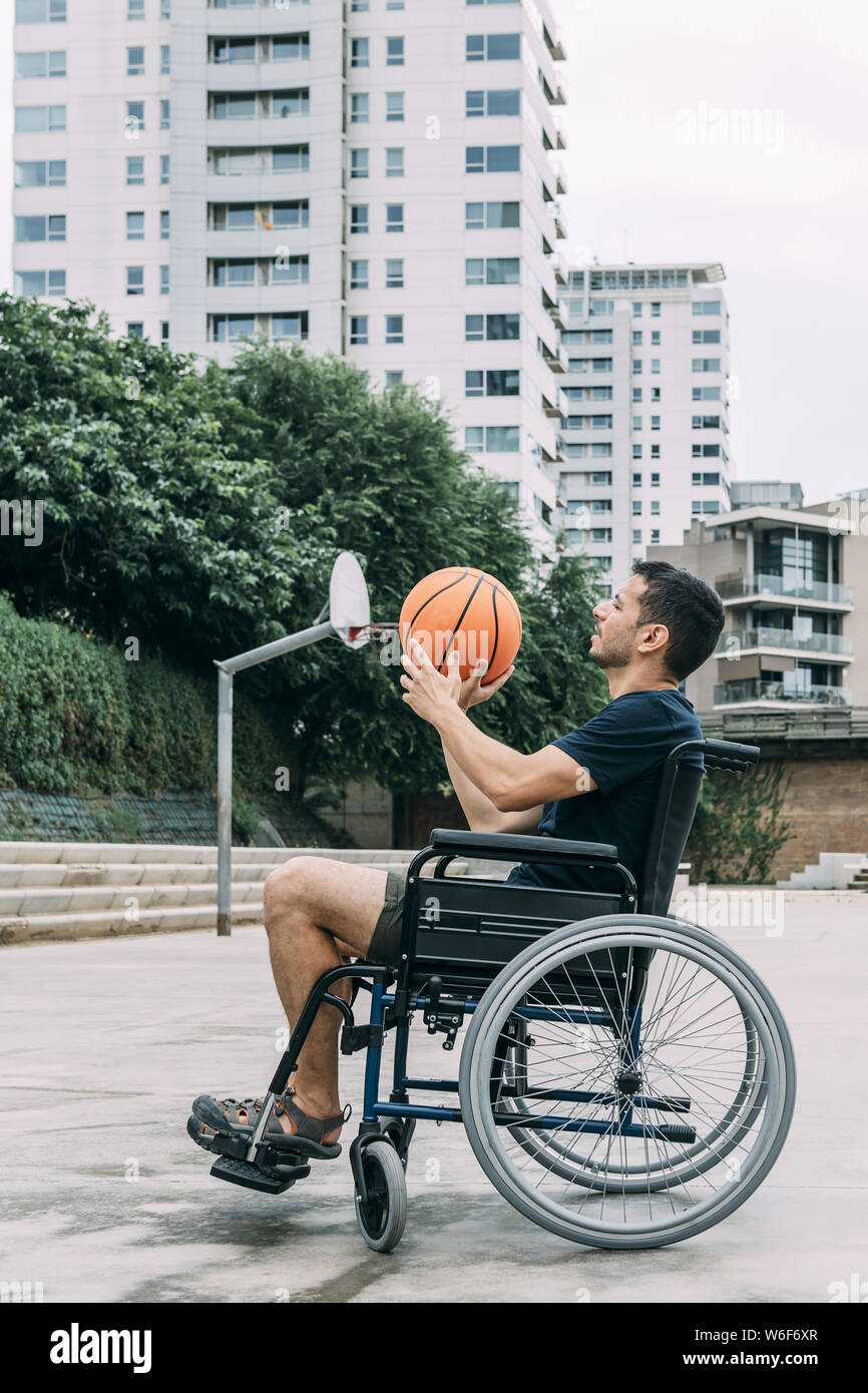 disabled man in wheelchair playing basketball alone, concept of