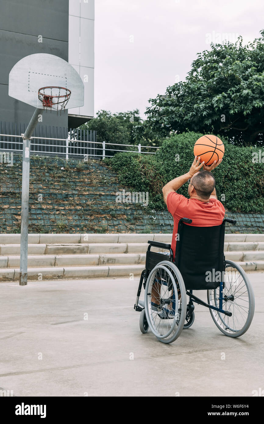 disabled man in wheelchair playing basketball alone, concept of