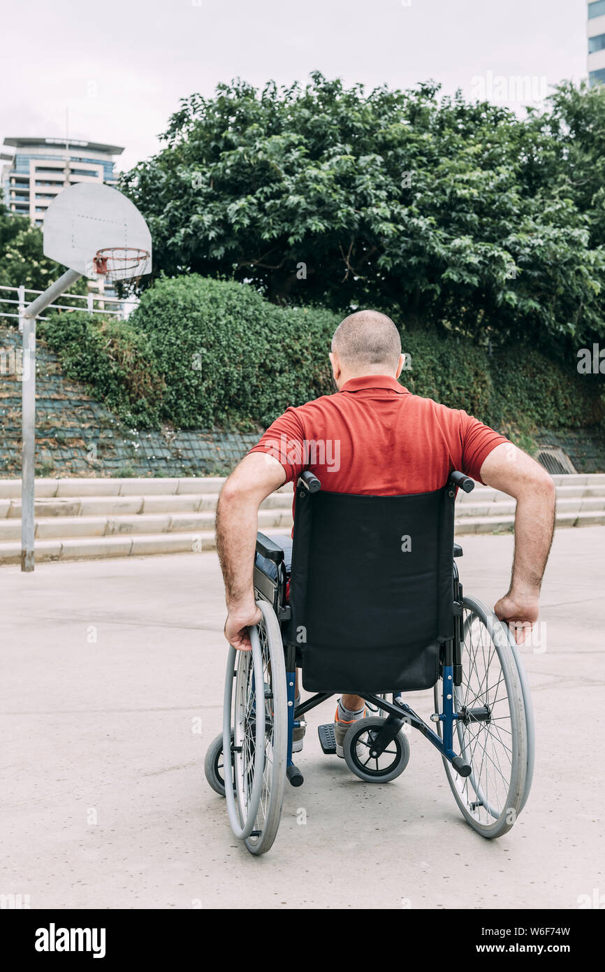 disabled man in wheelchair playing basketball on the court, concept of adaptive sports and physical activity, rehabilitation for people with physical Stock Photo