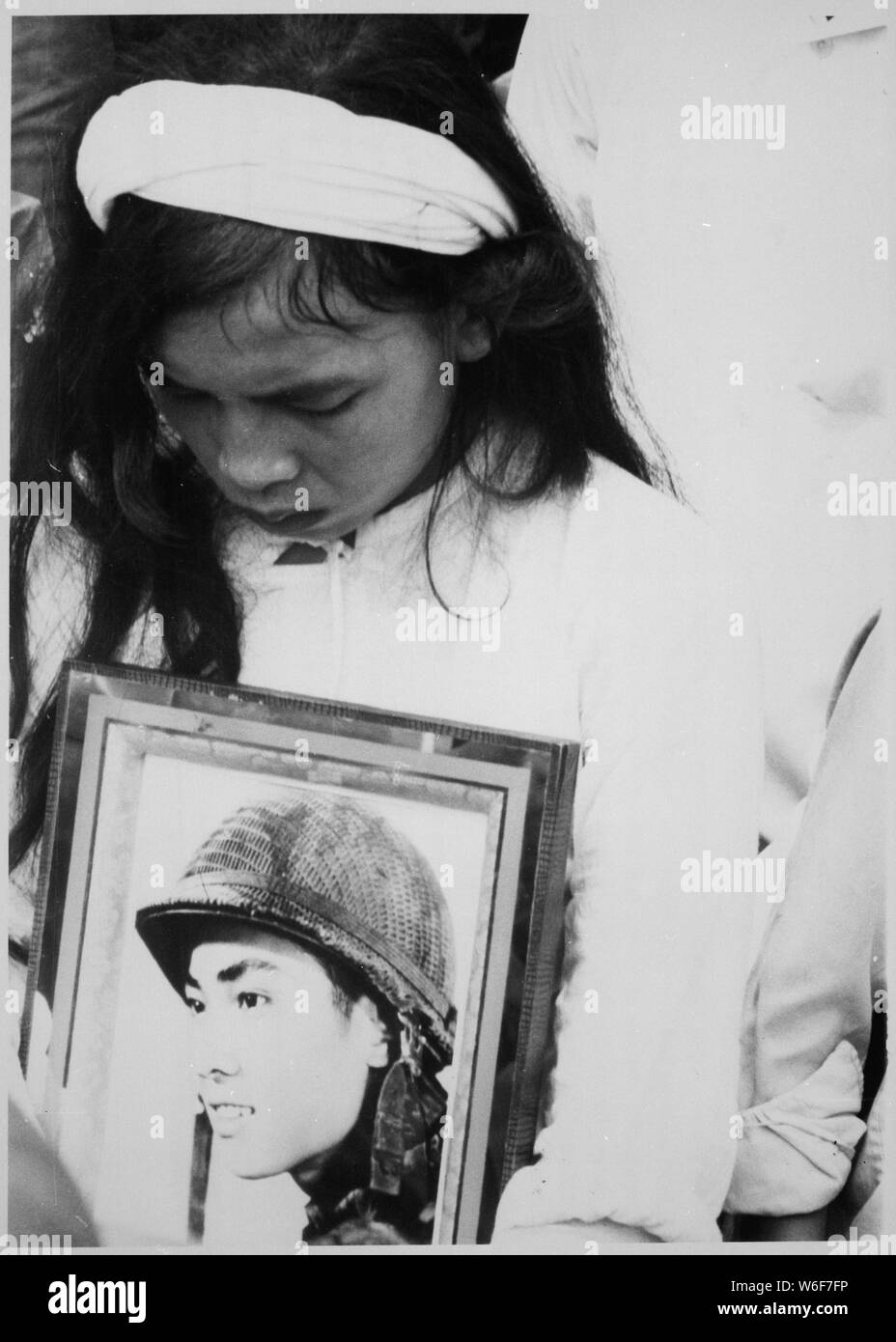 Almost 400 men, women and children massacred by the Viet Cong during Tet 1968 were mourned at a common-grave burial on October 14. This young widow, carrying a photograph of her missing husband, mourns at the mass funeral service. Hue, 1968., 1958 - 1974; General notes:  Use War and Conflict Number 427 when ordering a reproduction or requesting information about this image. Stock Photo
