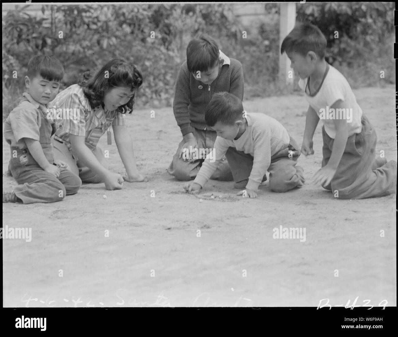 Arcadia, California. Like all youngsters in this country, children of Japanese ancestry enjoy a gam . . .; Scope and content:  The full caption for this photograph reads: Arcadia, California. Like all youngsters in this country, children of Japanese ancestry enjoy a game of marbles. An evidence of how completely western is the new generation, they even all allow the women folk to participate. Stock Photo