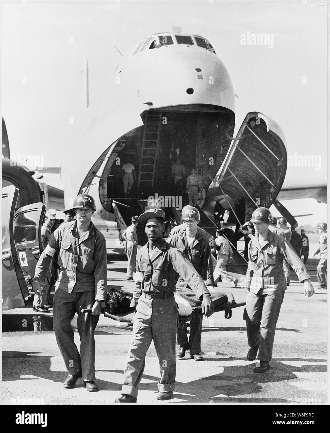 Army medics carry wounded UN personnel to waiting ambulances, after the patients' arrival at this Tokyo base in the U.S. Air Force C-124 in the background. The C-124, the largest cargo plane operating on the Korean airlift, carries as many as 135 patients. Forty of the patients on this flight, critically wounded, were flown to Camp Drew Hospital near Tokyo in C-47's of the Royal Thailand Air Force. The trip, which took only 20 minutes, would have required six hours by road. Stock Photo
