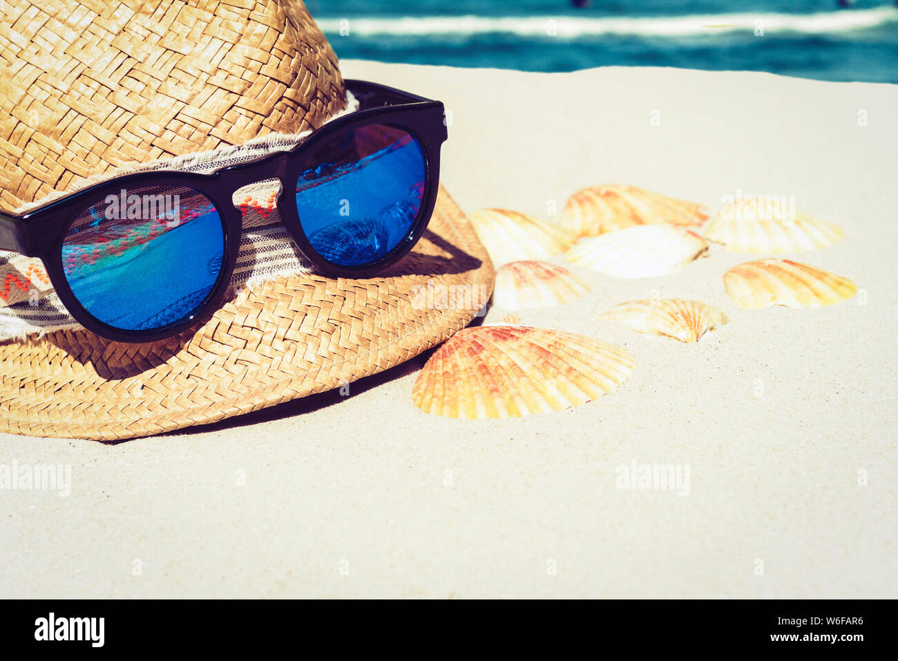 Vintage summer wicker straw beach hat and sun glasses on the sand with ...