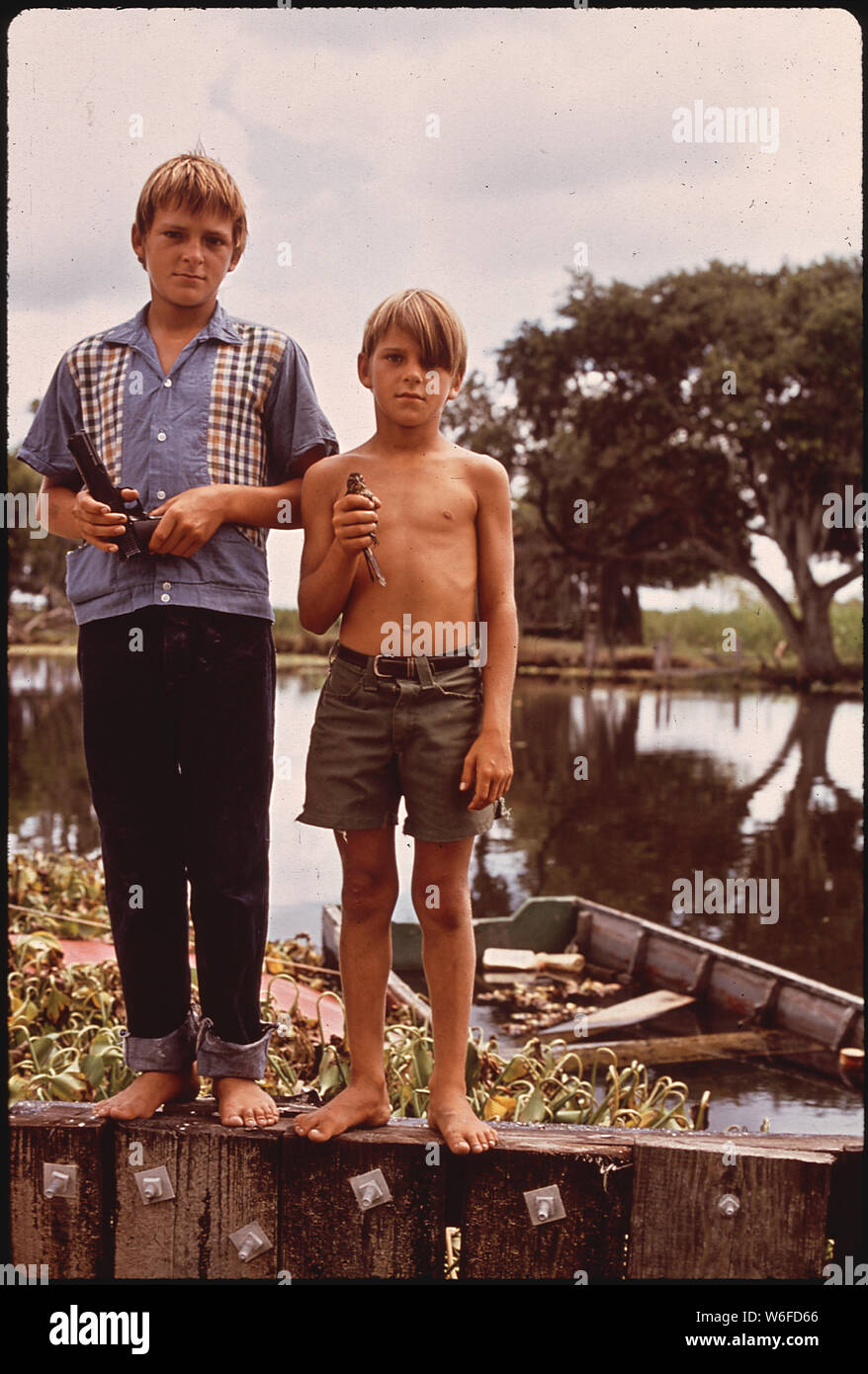BOYS WITH AIRGUN AND BIRD. THESE FISHERMEN'S SONS LIVE IN BAYOU GAUCHE, DEEP IN THE WETLANDS OF LOUISIANA Stock Photo
