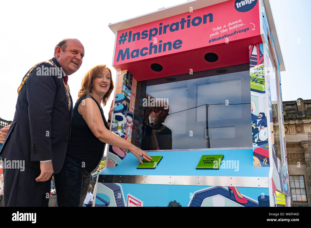 Edinburgh, Scotland, UK. 31 July 2019. Frank Ross, Lord Provost of Edinburgh  and Shona McCarthy, Chief Executive of of the Edinburgh Festival Fringe Society proclaimed the start of the 2019 Fringe by pushing the button on the new colourful arcade style Fringe Inspiration Machine on The Mound in Edinburgh today. The new Inspiration Machine is designed to help out audiences who might be having trouble deciding which shows to see from the diverse programme, by delivering three randomised suggestions of Fringe shows at the push of a button. Stock Photo
