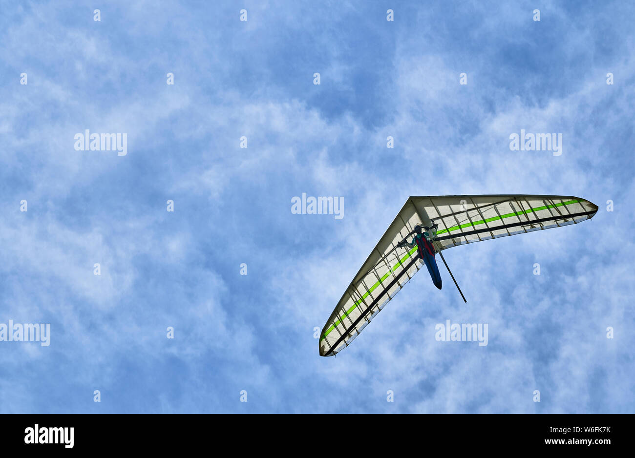 A single hang glider among the clouds high up in the sky. Side view. Stock Photo