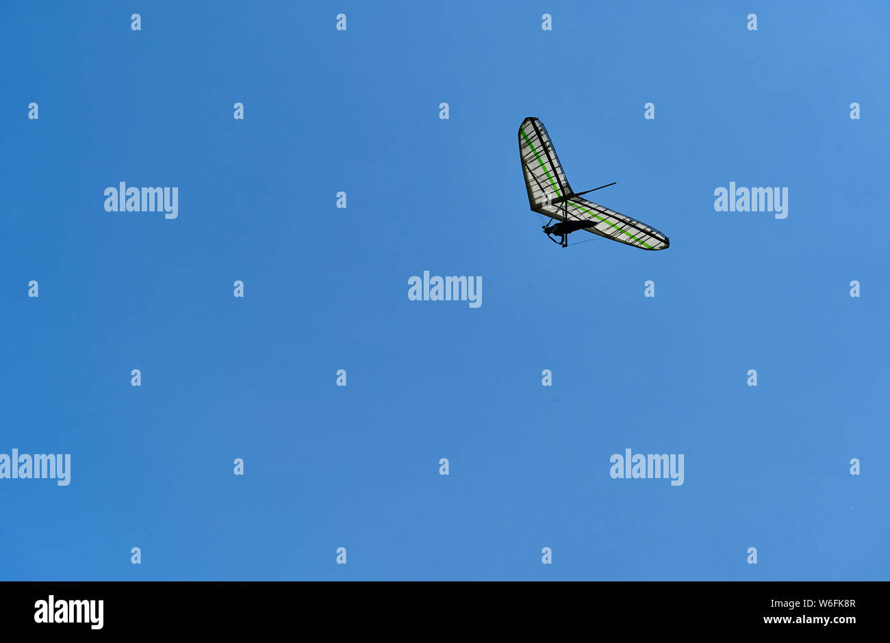 A single hang glider among the clouds high up in the sky. Side view. Stock Photo