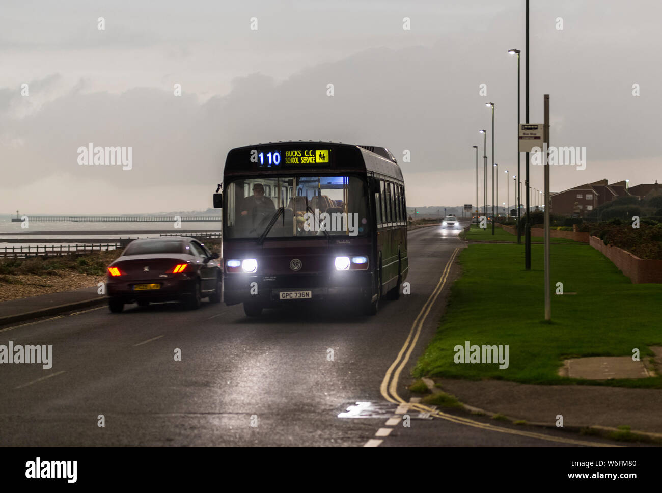 Old bus used as a school bus in the evening or at night, in the UK. Stock Photo