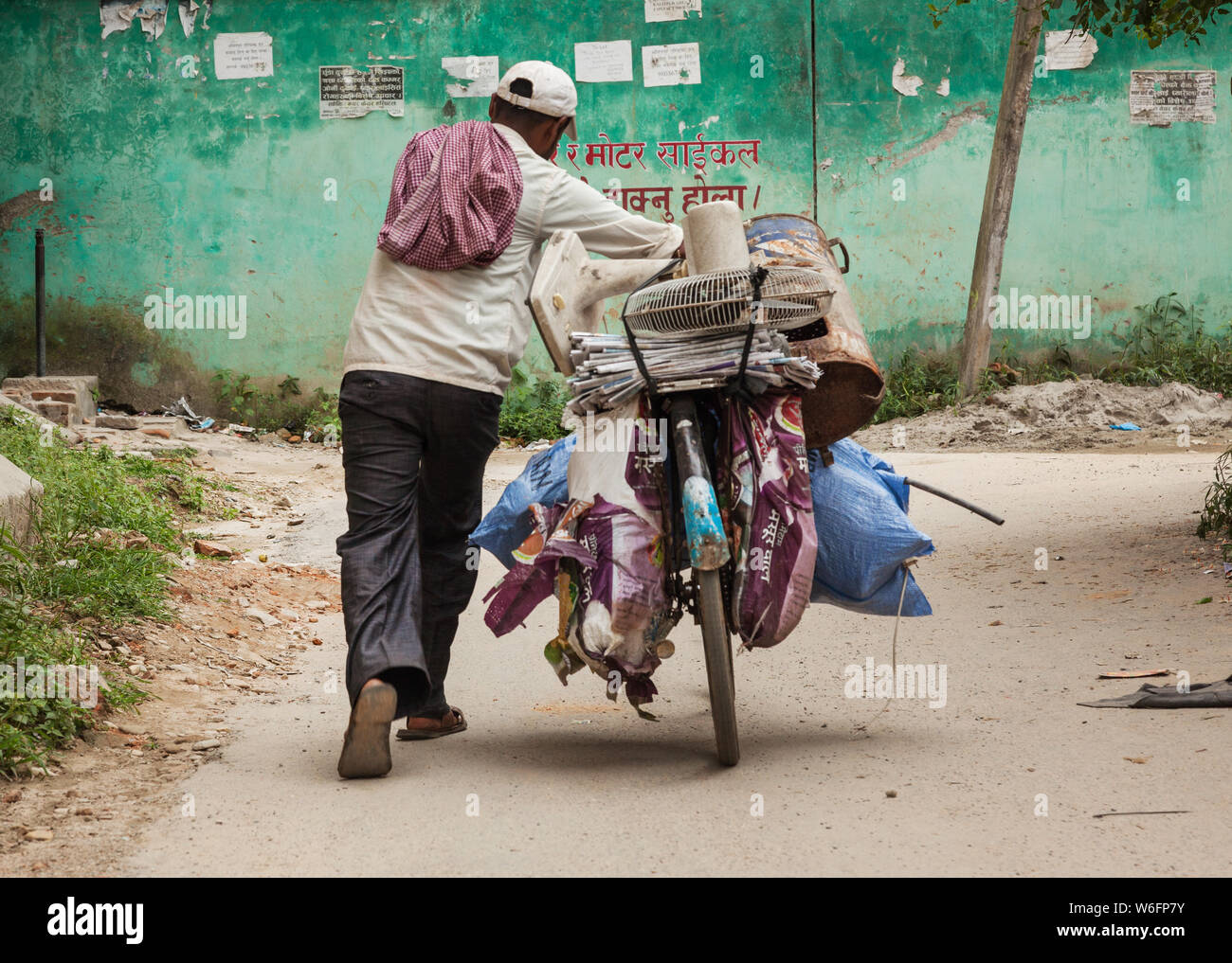 Man pushing his laden bicycle along a back street in Kathmandu, Nepal. Stock Photo
