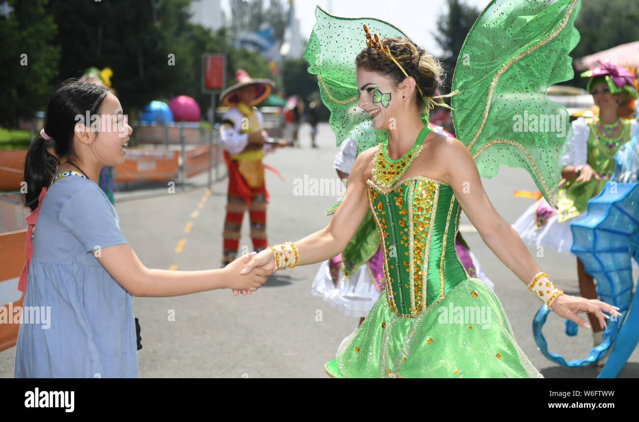 (190801) -- CHANGCHUN, Aug. 1, 2019 (Xinhua) -- Lazara Maria Gonzalezgil (R) shakes hands with a tourist at the movie themed amusement park she works for in Changchun, northeast China's Jilin Province, Aug. 1, 2019. Lazara Maria Gonzalezgil is a 25-year-old Cuban dancer born in Villa Clara. Seeking to go further in her career and for a better future, Lazara came to China in 2017 and soon got signed by a Chinese culture and education company. In the past two years, she has traveled as a dancer to many cities across China, including Harbin, Beijing, Jinan, Shanghai, Guangzhou and Haikou. Nowaday Stock Photo