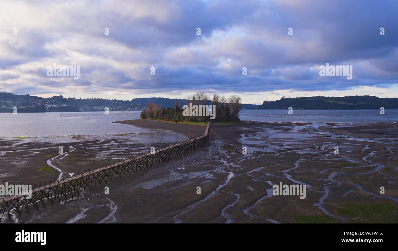 Aerial view of the iconic Aucar Island that has a bridge made of wood. This island is near the town of Quemchi in the Chiloé archipelago Stock Photo
