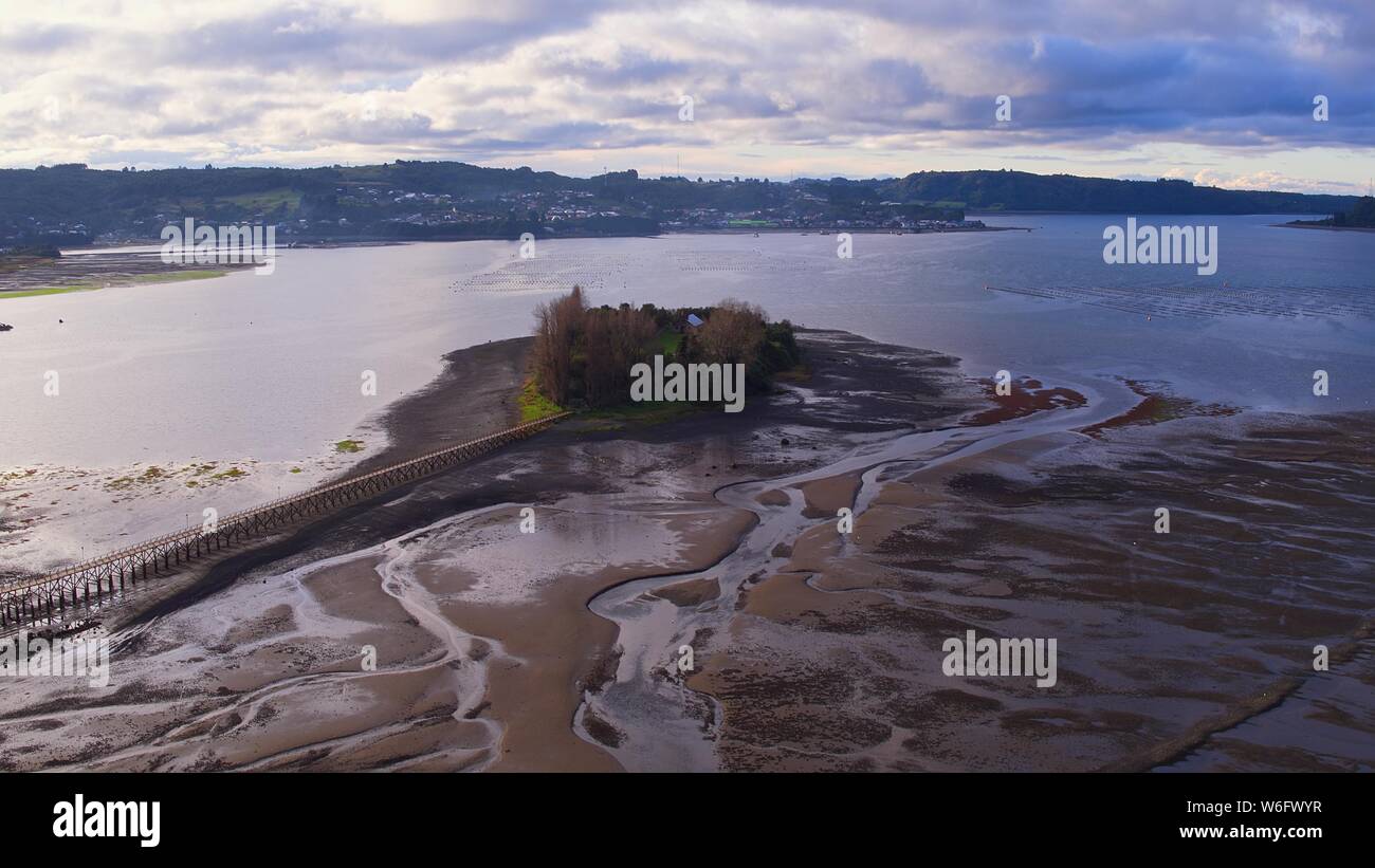 Aerial view of the iconic Aucar Island that has a bridge made of wood. This island is near the town of Quemchi in the Chiloé archipelago Stock Photo
