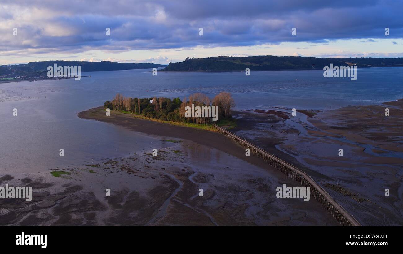 Aerial view of the iconic Aucar Island that has a bridge made of wood. This island is near the town of Quemchi in the Chiloé archipelago Stock Photo