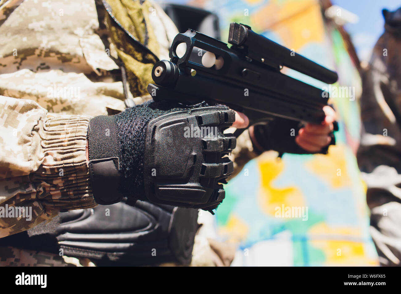 Man in camouflage suit stands against the paintball area with his