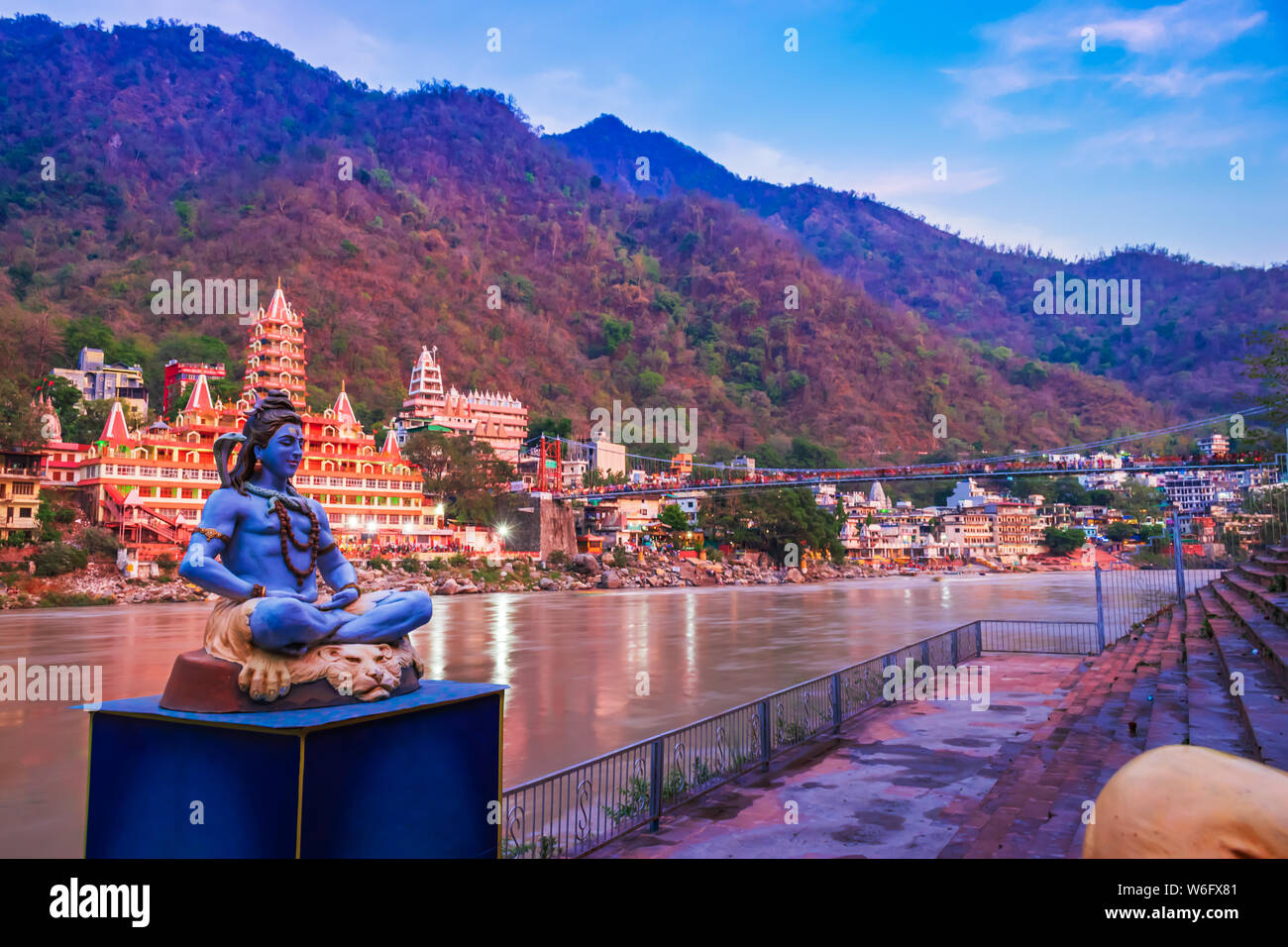River Ganges, the famous bridge Laxman Jhula surrounded by temples and mountains around in Rishikesh, India Stock Photo