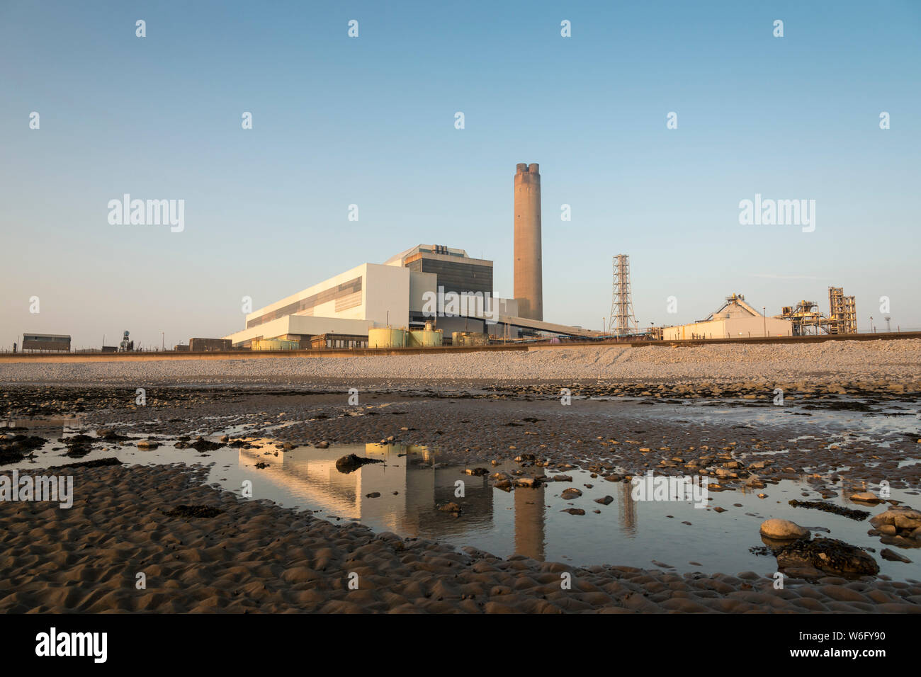 A view of Aberthaw coal fired power station, from the adjacent beach, when it is bathed in pale evening sunlight under a cloudless blue sky. Stock Photo