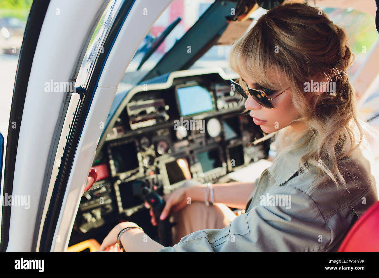 Female pilot in cockpit of helicopter before take off. Young woman
