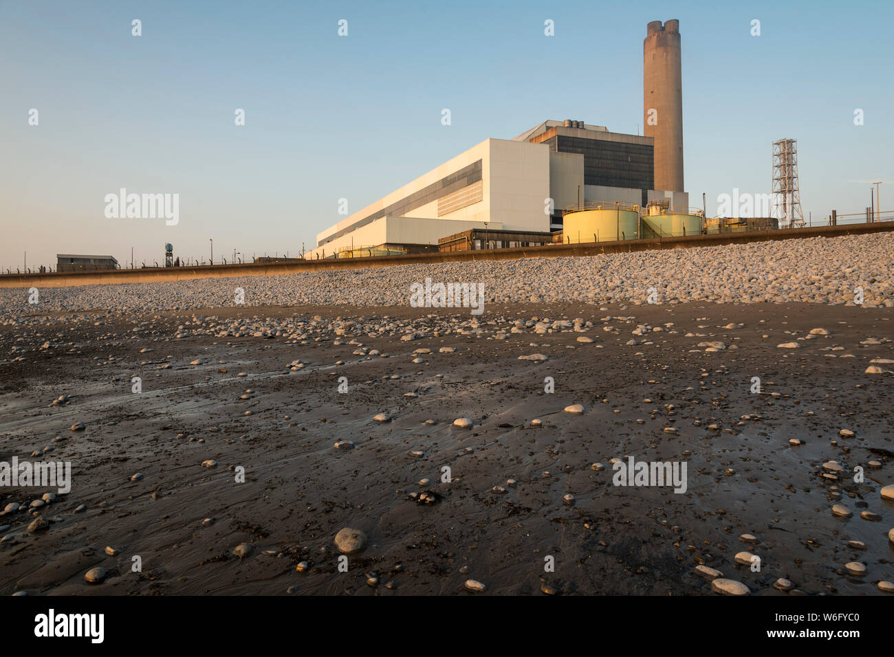 A view of Aberthaw coal fired power station, from the adjacent beach, when it is bathed in pale evening sunlight under a cloudless blue sky. Stock Photo