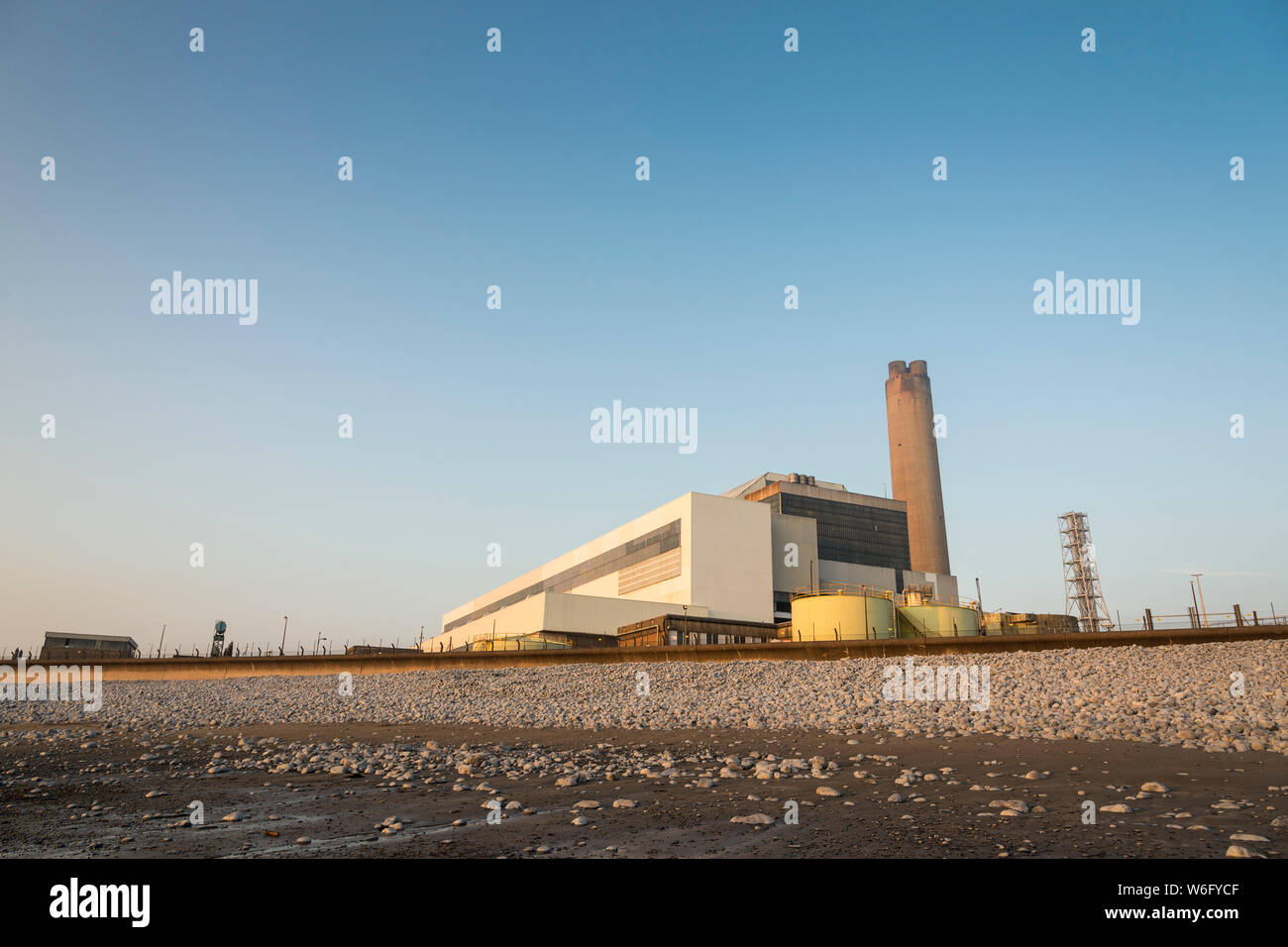 A view of Aberthaw coal fired power station, from the adjacent beach, when it is bathed in pale evening sunlight under a cloudless blue sky. Stock Photo