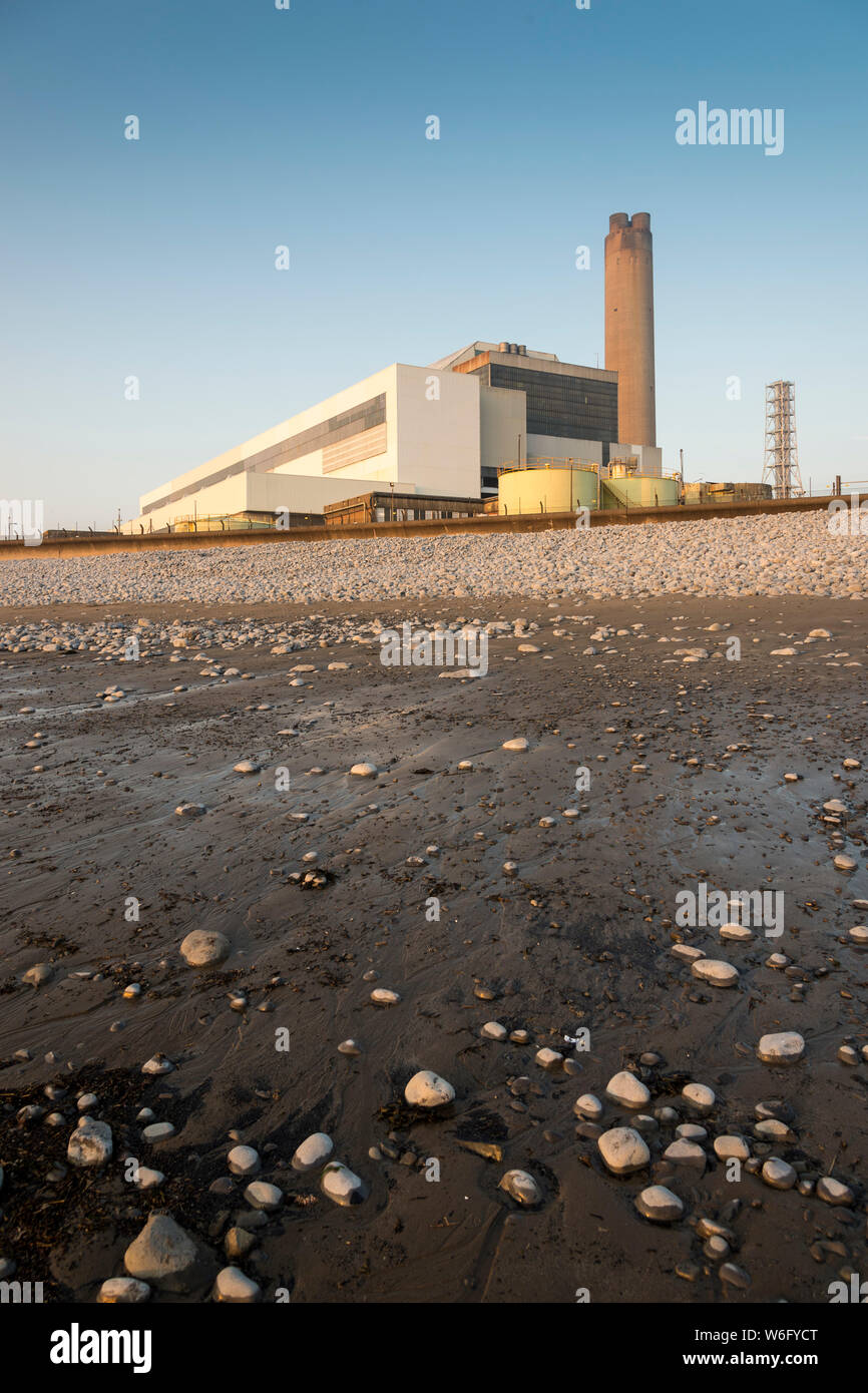 A view of Aberthaw coal fired power station, from the adjacent beach, when it is bathed in pale evening sunlight under a cloudless blue sky. Stock Photo