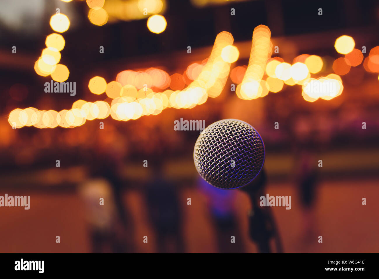 microphone on a stand up comedy stage with colorful bokeh , high