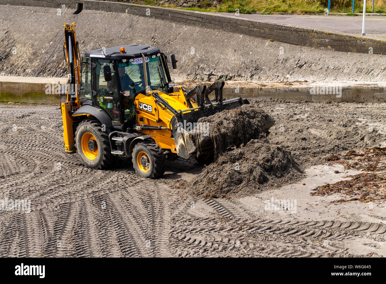 JCB Back Hoe cleaning up a beach. Stock Photo