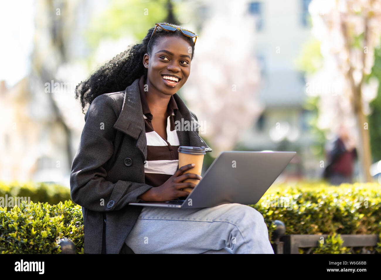 Happy relaxed african girl using a laptop in the street Stock Photo - Alamy