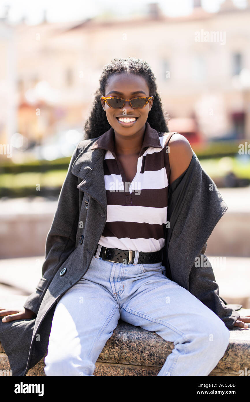 Beautiful african woman outdoors sitting in the street Stock Photo - Alamy