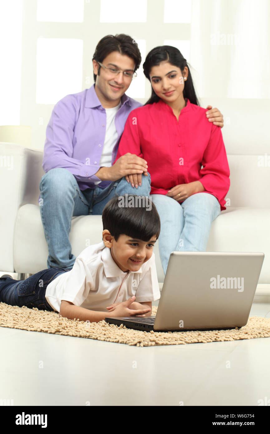 Boy using laptop with his parents sitting on couch Stock Photo - Alamy