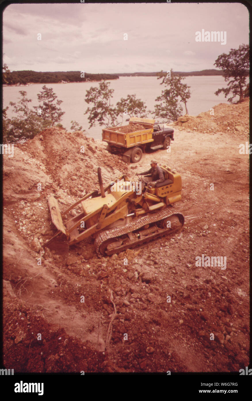 DIGGING FOUNDATIONS FOR A HOME DIRECTLY ABOVE LAKE AT SUNRISE BEACH ON THE LAKE OF THE OZARKS. THE LAND HERE FALLS OFF STEEPLY TO THE SHORE, AND THIS DEGREE OF SOIL DISTURBANCE INCREASES LIKELIHOOD OF EROSION Stock Photo