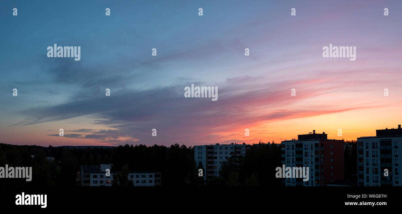 Colorful sunset clouds at dusk over city buildings Stock Photo