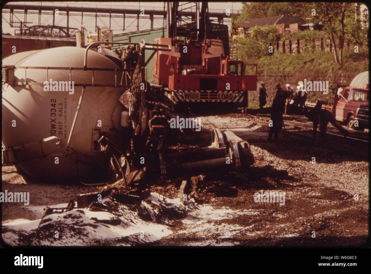 DOW CHEMICAL TANKS TRANSPORTING PLASTIC GRANULES DERAILED AND OVERTURNED ON PENN CENTRAL RAILROAD TRACKS ABOVE SCRANTON ROAD. FORTUNATELY, ONLY SPILLAGE (THE WHITE GRANULES) AND PROPERTY DAMAGE ENSURED. HERE RAILROAD CREW IS CLEANING UP Stock Photo
