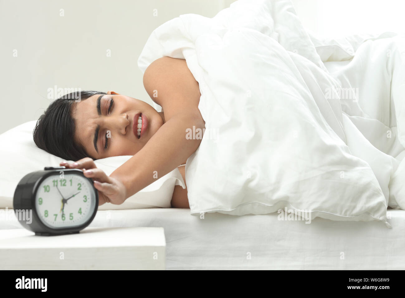 Woman turning off alarm clock Stock Photo Alamy