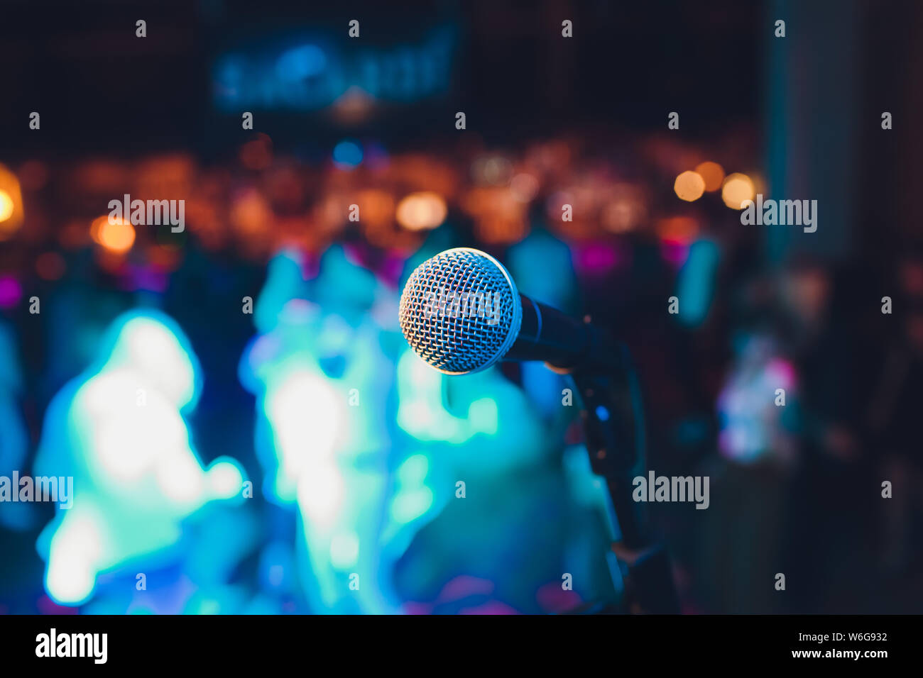 microphone on a stand up comedy stage with colorful bokeh , high