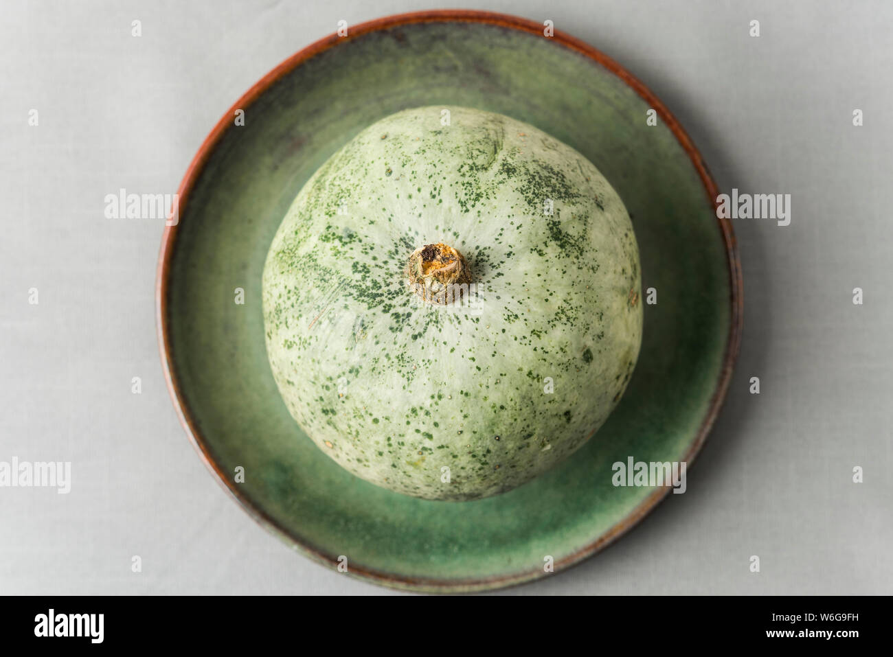 Crown prince winter squash on rustic green plate, overhead shot. Stock Photo