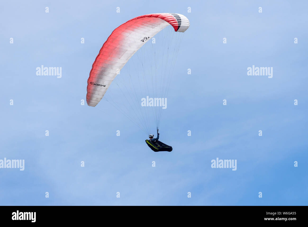 Gliding In Blue Sky - A paraglider pilot sitting comfortably in cushioned harness and enjoying flying in blue sky. Lookout Mountain, Golden, CO, USA. Stock Photo