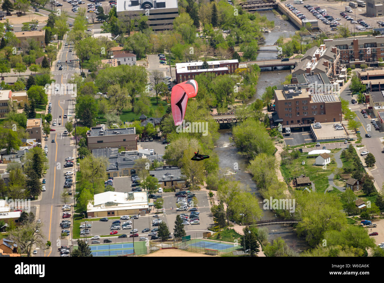 Fly Above Golden - A red paraglider flying above Clear Creek at center of city of Golden, Colorado, USA. Stock Photo